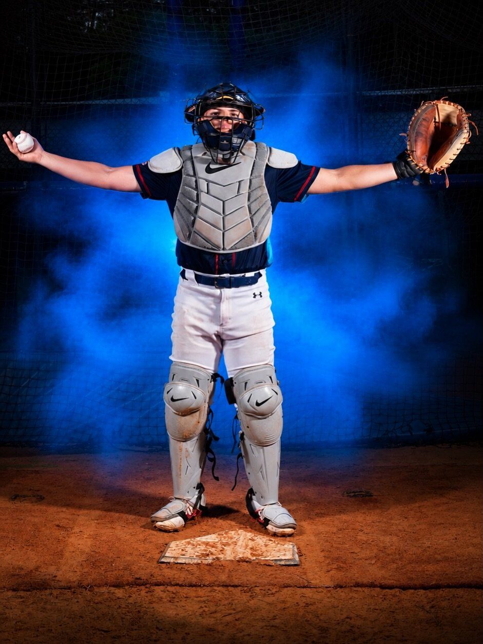 Catcher standing with arms open, ball in one hand and glove in the other
