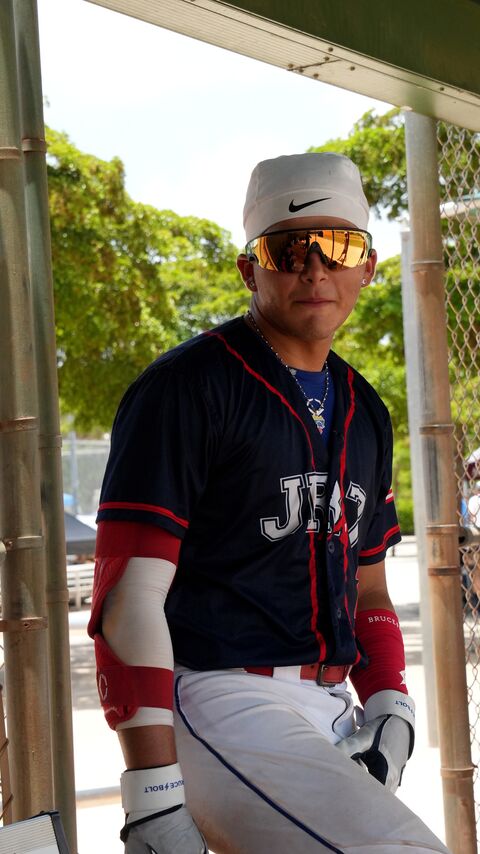 Baseball player in a navy uniform next to the dugout