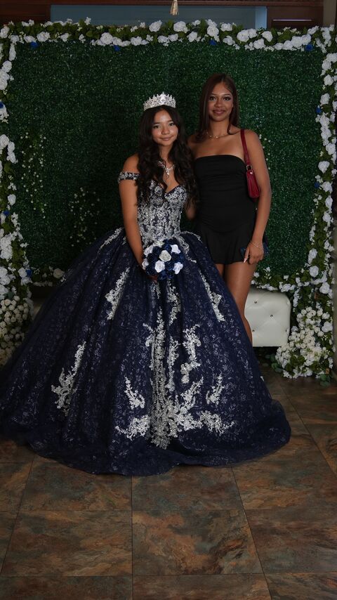 The quinceañera with a guest under the white flower arch